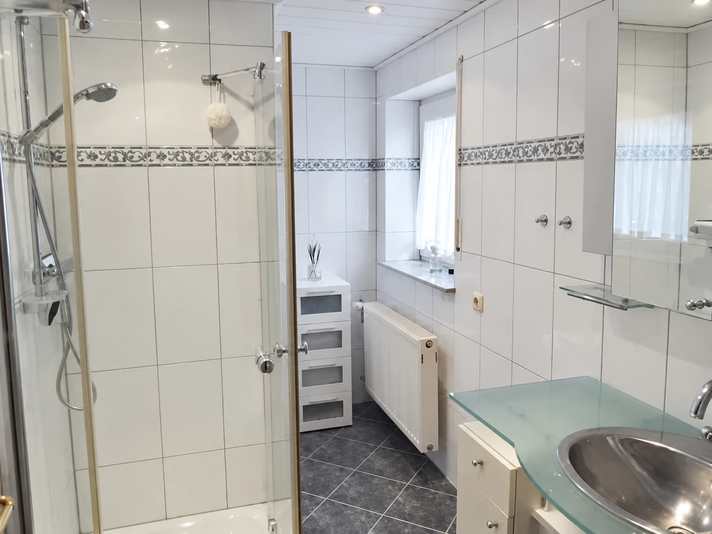 Gefliestes Badezimmer mit Dusche, Waschbecken und WC